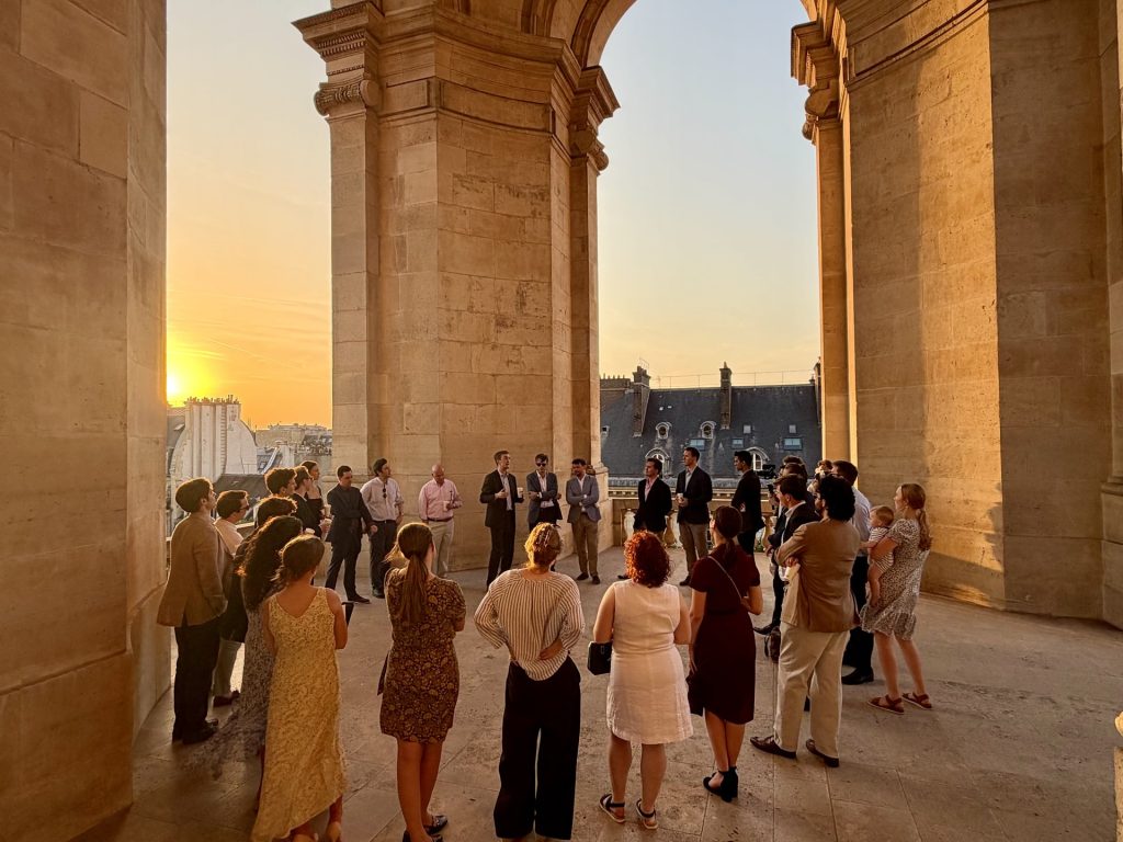 Participants gathered in a circle beneath a stone arcade at sunset
